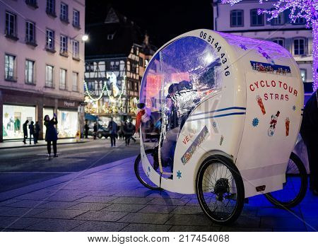 STRASBOURG FRANCE - NOV 29 2017: Rickshaw green transportation at night parked in center of Strasbourg Place Gutenberg waiting for its clients for a romantic promenade Cyclo Tour Stras