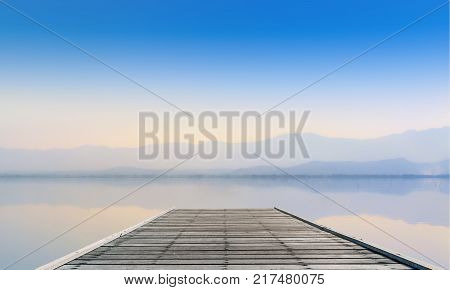 Calmness Lake with mountain and wooden plank pier in sunset