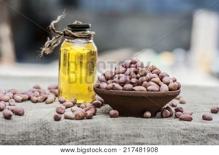 [arachis Hypogaea] Raw Groundnut In A Clay Bowl With Groundnut Oil On A Gunny Background.;