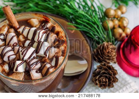 Hot chocolate in glass topped with marshmallow and chocolate sauce. Homemade hot chocolate or cacoa on wood table in top view copy space with Christmas theme background. Concept to present Christmas drink. Delicious hot chocolate ready to served.