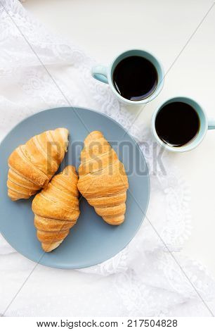 two cups of coffee with croissants on the background of laces on a white background