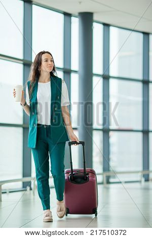 Young woman in international airport walking with her luggage.