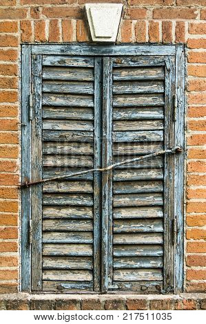 Blue wooden old window shutters on a vintage brick wall.