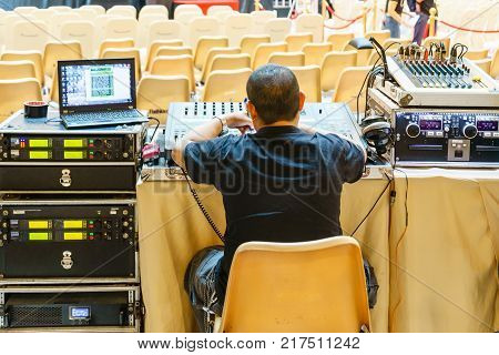 Sound technician and lights technicians control the music show in concert.Professional audio light mixer controller panel.Pro equipment for concerts.Stage lighting control.Hand adjusting audio mixer