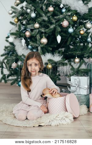 The girl sits at the tree and looks at the gifts. New Year holidays. The time to realize dreams. A gift in the box. New Year's Symbol