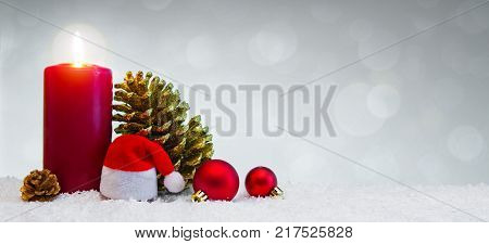 Avent candle and christmas decoration isolated on gray background. Christmas background with snow, candle and Santa Claus hat.