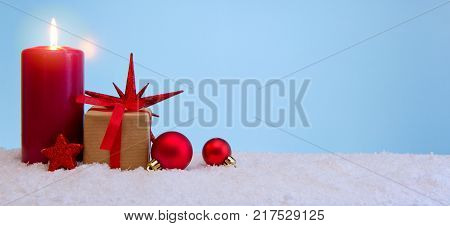 Avent candle and christmas decoration isolated on blue background. Christmas background with snow, candle and gift box .