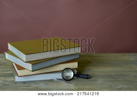 Four stamp albums books bunch, loupe and tweezers on wooden table and bordeaux background