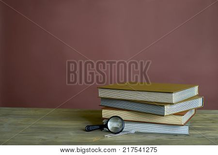 Four stamp albums books bunch, loupe and tweezers on wooden table and bordeaux background