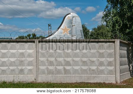 RUSSIA MOSCOW REGION MONINO - August 09 2017: Museum of the air force. the tail of the old military aircraft with a red star is visible from behind a concrete fence with barbed wire on blue sky background
