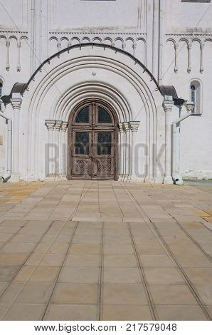 old carved oak door in arched opening in a white stone building decorated with ornaments