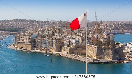 Senglea fortified city and Fort Saint Michael across Grand Harbour from Valletta Malta. The photo incorporates a Maltese flag.