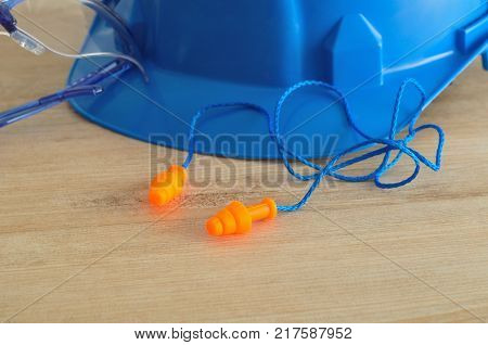 A hard hat safety glasses and a pair of ear plugs isolated on a wooden background