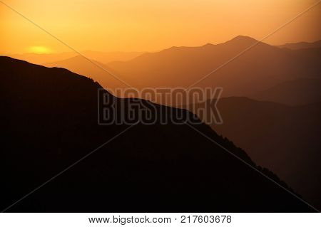 Natural background with mountains at the sunset or sunrise in yellow and orange colours