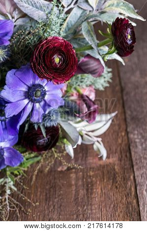 natural elements, decoration, celebrating concept. close up of puffy buds of different flowers, collected in the single bouquet, there are dark red persian battercups, lilies and great lilac anemons