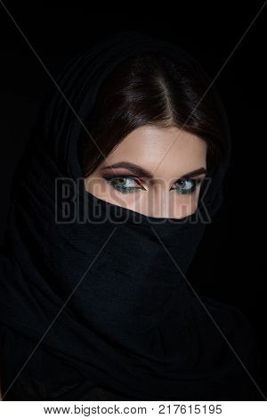 Beautiful muslim woman in niqab traditional veil against on dark background