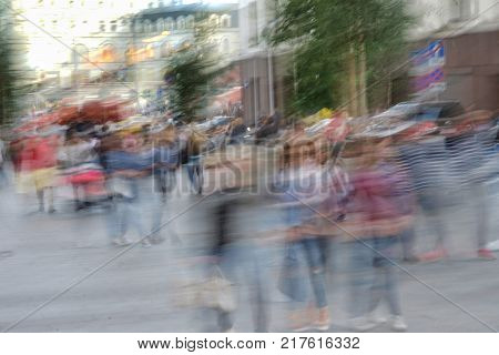Abstract crowd of anonymous people walking on the city streets, summer sunny day, blurred urban background