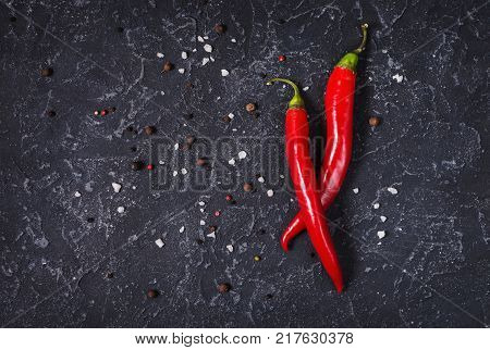 Red hot chili pepeprs and peppercorns on black stone background, top view and copy space