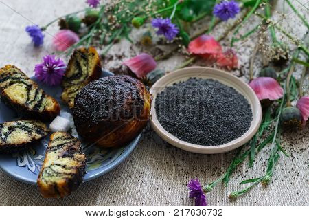 Sweet bun with flax seed and poppy and cup of tea on table.
