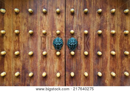 Chinese traditional doorknob and wooden doors. Old handle of metal on a wooden old door. Door knocker in the shape of a lion.