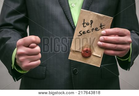 The spy. Secret service. Detecive agent holds pistol gun in his hands and secret documents with compromising evidence behind his back. Secret meeting. Retro gangster isolated.