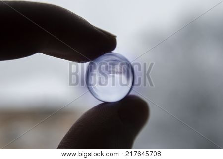 Look to inverted world through the blue glass ball in fingers.