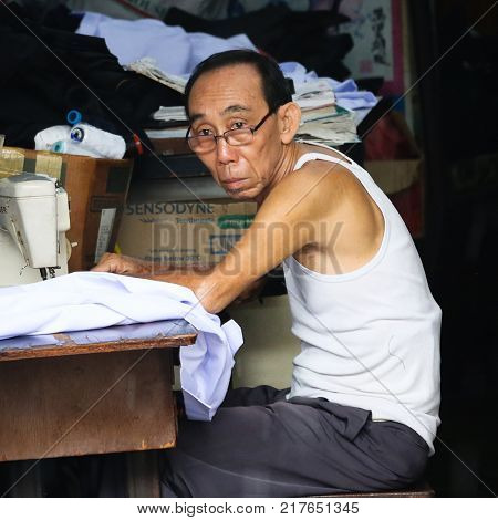 MALACCA MALAYSIA SEPTEMBER 20 2017: Old man sewing clothes in Malaysia's colorful and historic World Heritage City, Melaka