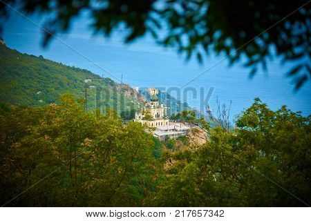 View through green leafs to the christian church and sea