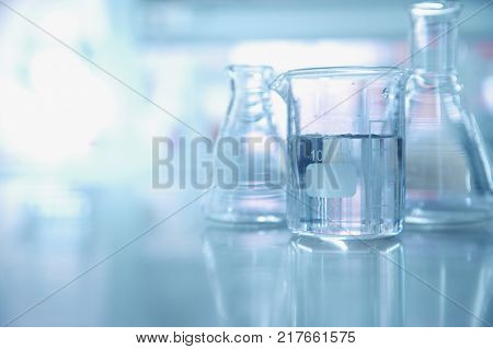 experiment water in beaker and flask in blue chemistry science laboratory background