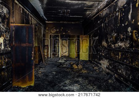 Burned by fire interior of old hospital. Charred walls and doors of corridor.
