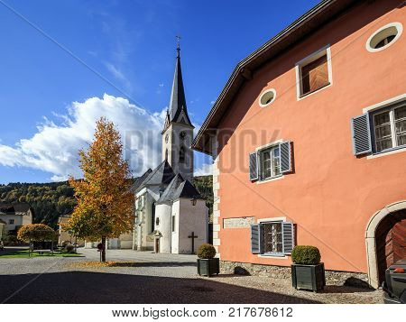 Beautiful paved street with old residential houses and gothic parish church of Assumption. Gmuend in Kaernten, district of Spittal an der Drau, federal state of Carinthia, Austria