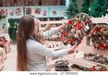 customer woman choosing Christmas decorations. Various choice of New Year's wreath with decorations