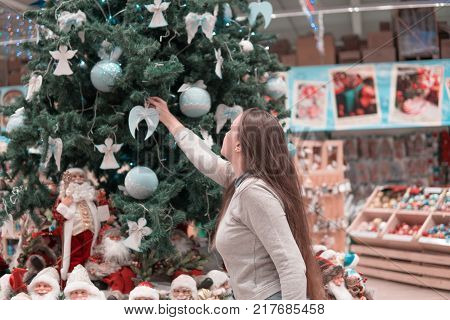 beautiful girl decorating Christmas tree with decoration balls.