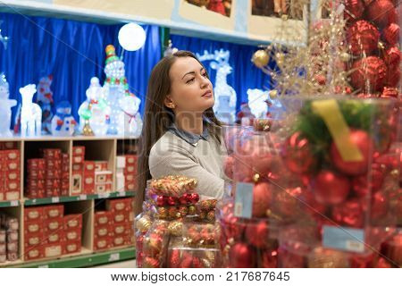 customer girl choosing red Christmas tree decoration balls. difficult decision. Various choice