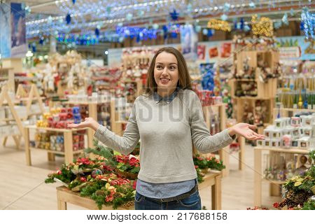 Cheerful girl choosing gifts for Christmas and New Year. she is at a loss from the variety of goods. difficult decision
