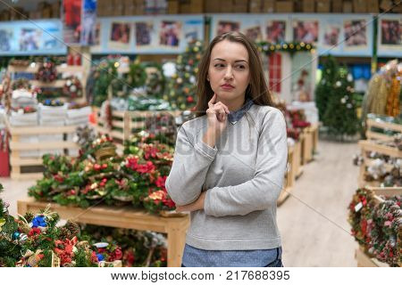 Emotional customer choosing gifts for Christmas and New Year. she is at a loss from the variety of goods. she is thinking