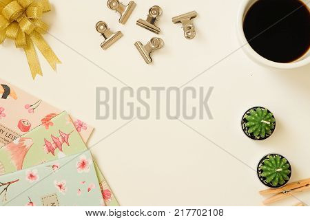top view of ribbin bow, coffee, notebooks, paperclip and cactus background