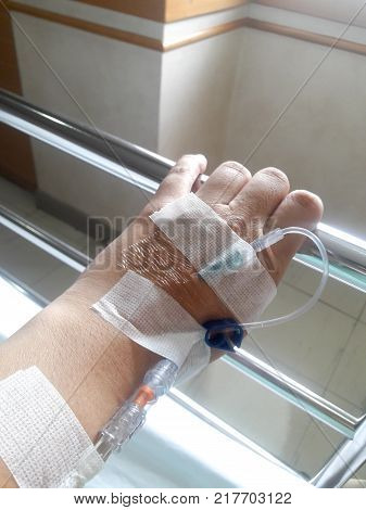Patient hand with the tube of normal saline infusion on white cloth background