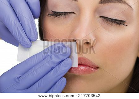The young woman reciving facial epilation keep  eyes closes
