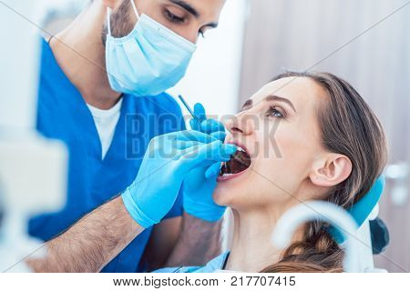 Side view of a young woman during painless teeth cleaning done in a modern medical center