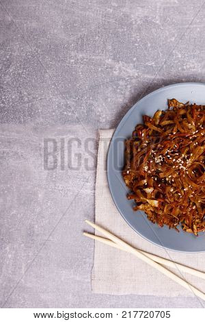A top view on a chinese food. Chopsticks and Chinese spicy sea kale with chilli and sause on the marble background. Close-up of objects. Food concept.