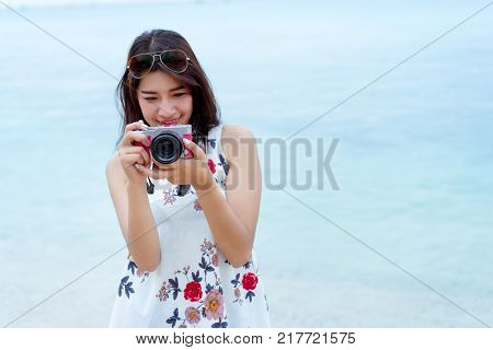 Asian woman taking photo with camera mirrorless at beach,Lifestyle hipster and travel relaxation,rest in summer season vacation concept, Selective camera focus