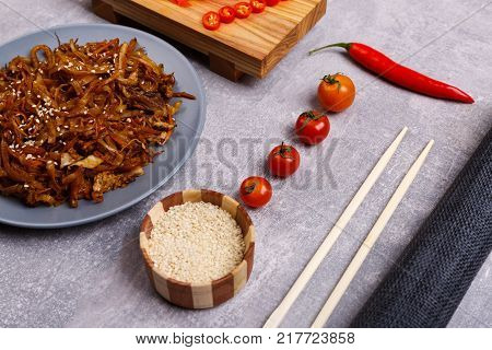A top view on a chinese food. Chopsticks, Chinese spicy sea kale with chilli and sauce on the marble background. Close-up of objects. Food concept.