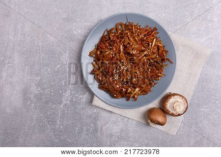 A top view on a chinese food. Chopsticks, Chinese spicy sea kale with chilli and mushrooms on the marble background. Copy space. Close-up of objects. Food concept.
