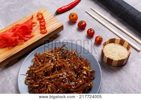 A top view on a chinese food. Chopsticks, Chinese spicy sea kale with chilli and sauce on the marble background. Close-up of objects. Food concept.