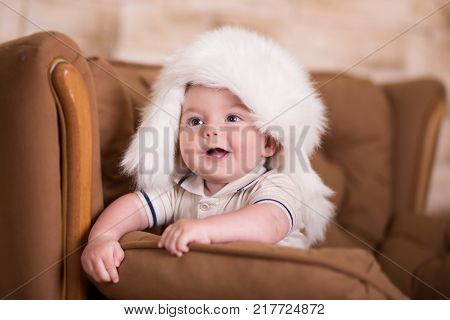 Happy Newborn Child Baby Boy With Pink Cheeks Posing On Hege Retro Casual Style Brown Couch Divan So