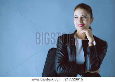 Portrait of beautiful young brunette woman in stylish black jacket on gray