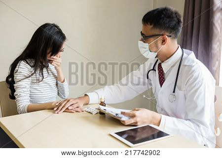 Asian doctor or physician cheer up and encourage sad patient woman by touching hand after reporting bad health result on the paper at hospital. Health care and Medical concept.