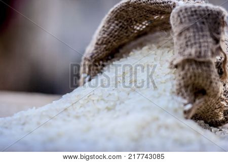 Raw organic riceOryza sativa coming out from a gunny bag.