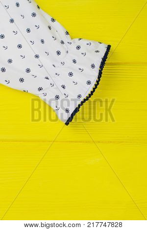 Ruffle cuff of girls blouse on yellow background. Nautical pattern and decorative navy edging. Fashionable clothes and beautiful details.